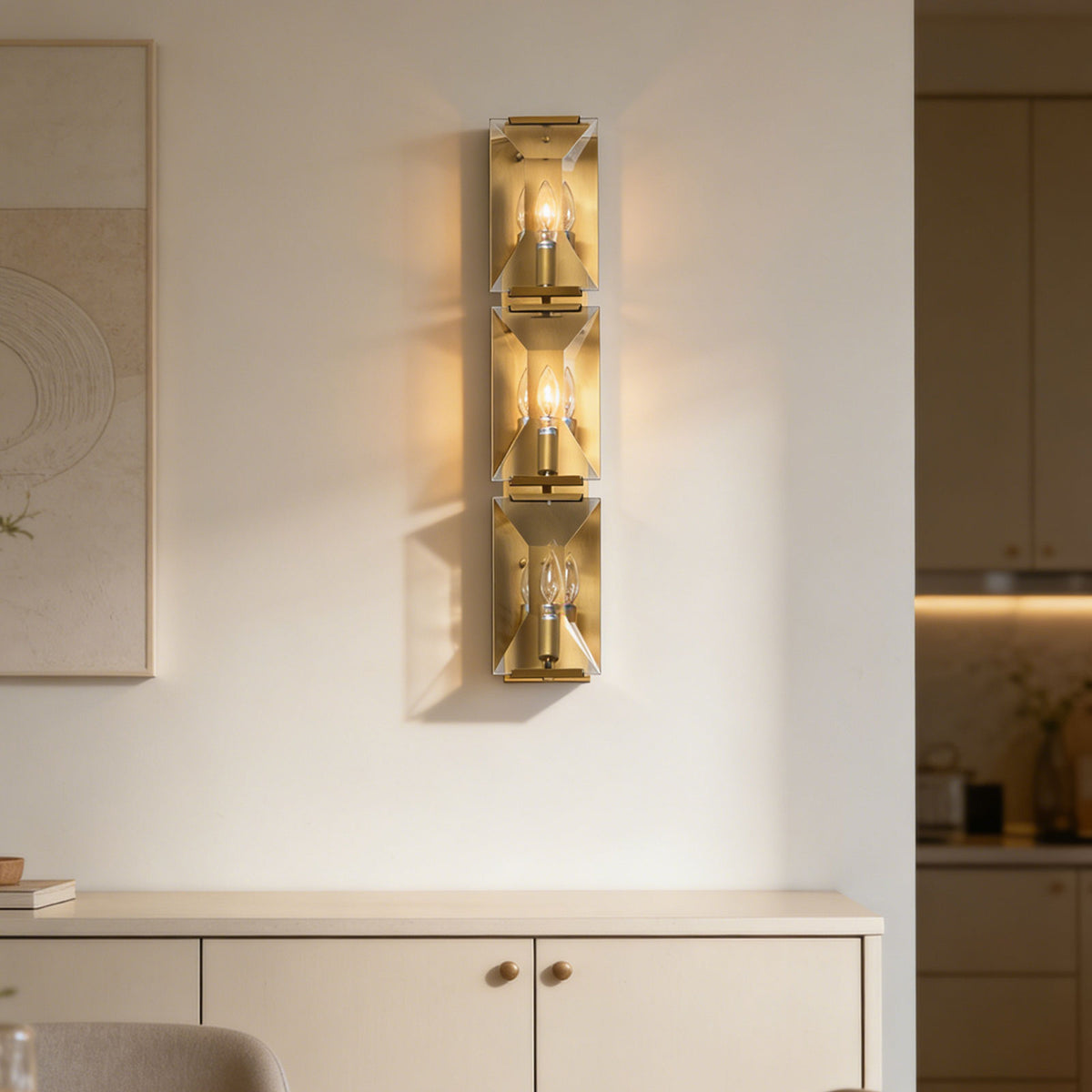 Three-headed crystal wall lamp mounted above a light wood cabinet in a modern interior.