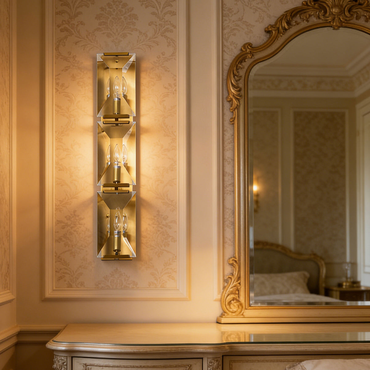 Three-headed crystal wall lamp mounted beside an ornate mirror in a vintage-style bedroom.