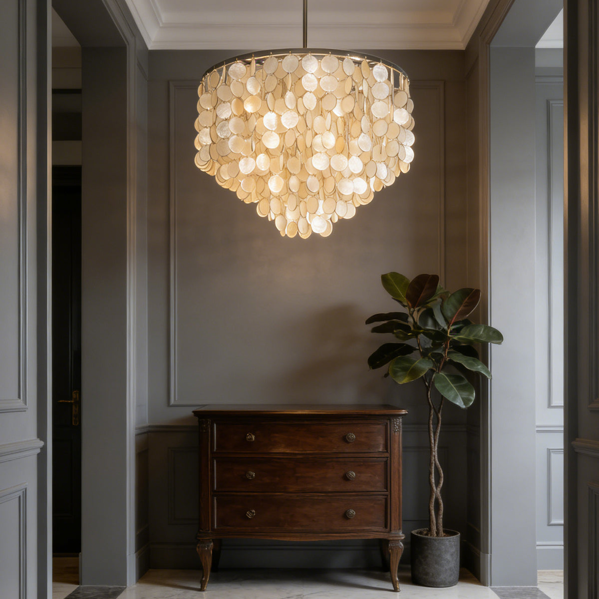 Tiered capiz shell chandelier in a neutral-toned entryway with a dark wooden dresser.