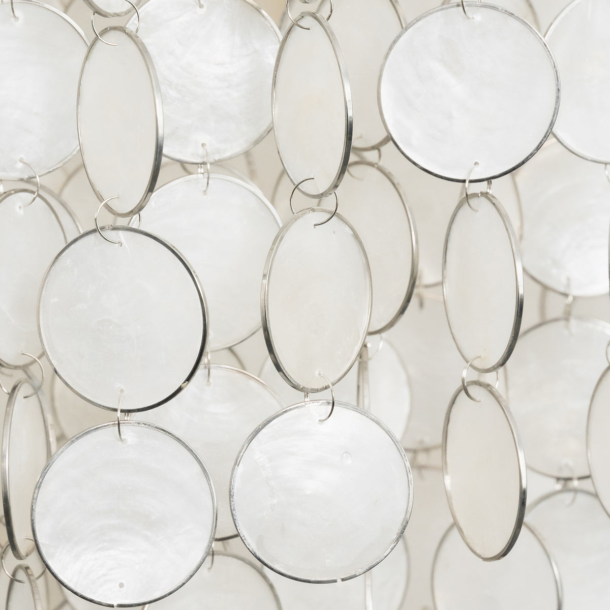 Close-up of the natural texture and iridescent finish of individual capiz shell discs on the chandelier.