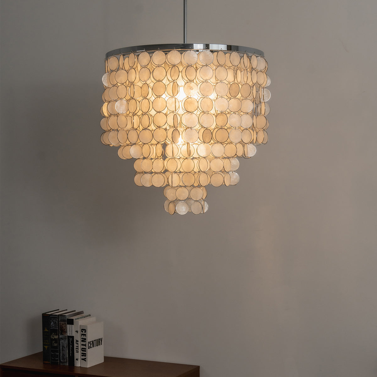 Lit tiered capiz shell chandelier casting a warm ambient glow in a cozy neutral-toned room.