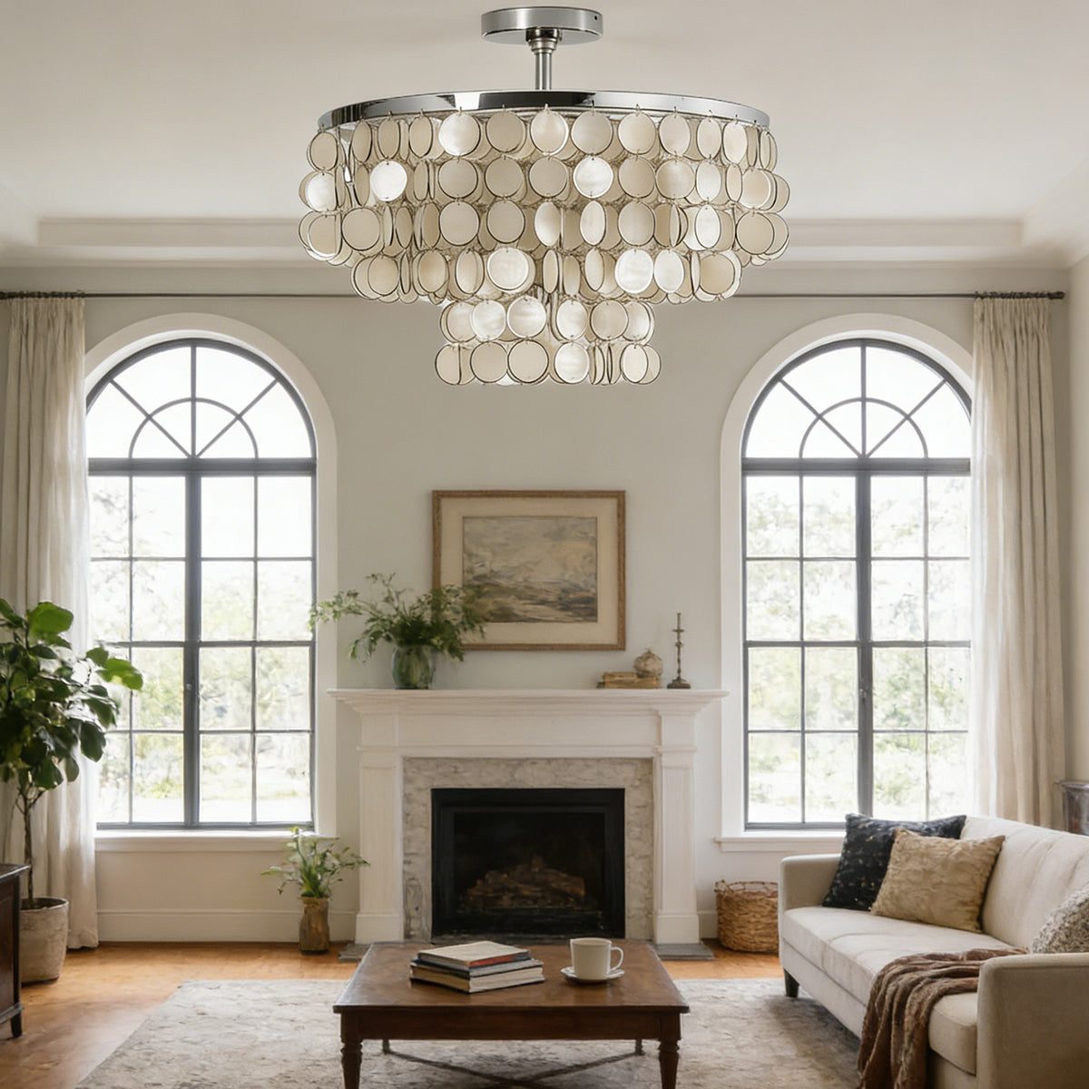 Tiered shell disc ceiling light hanging in a bright living room with arched windows and a fireplace.