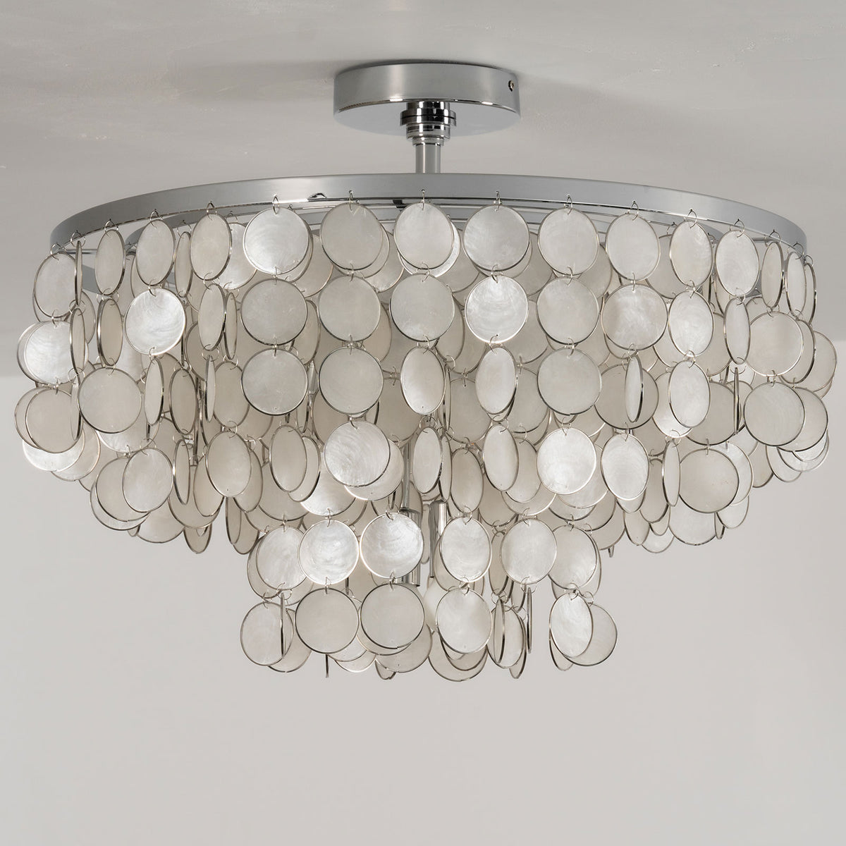 Low-angle view of the tiered shell disc ceiling light, isolated on a white background.