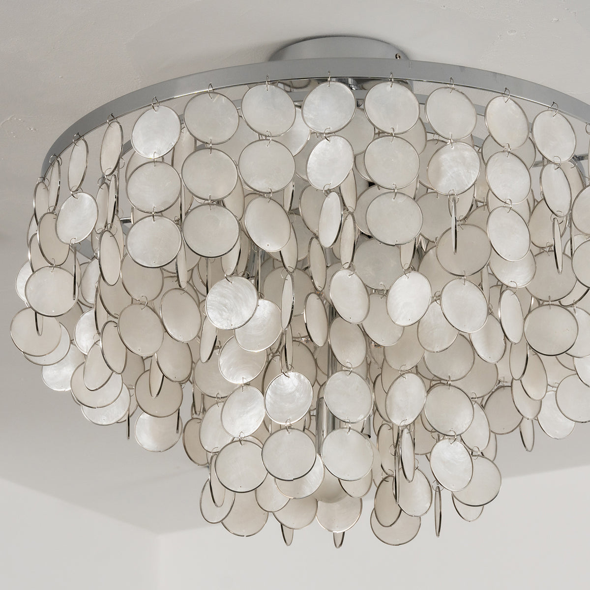 Tiered shell disc ceiling light against a light neutral background, showing its soft, layered design.