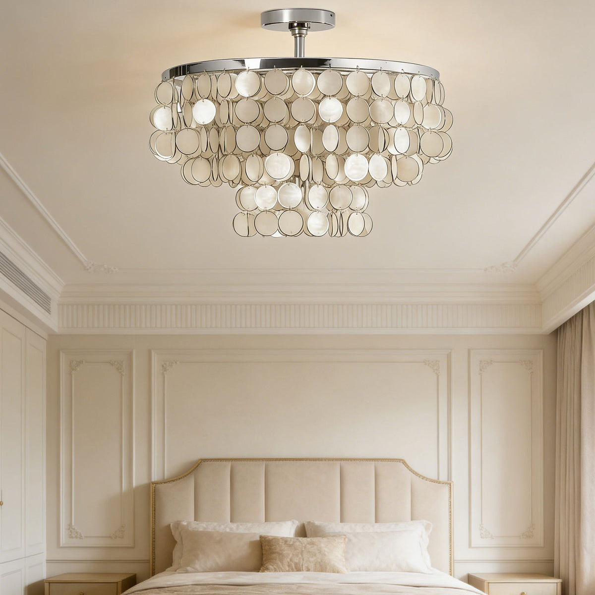 Tiered shell disc ceiling light above a tufted bed in a neutral-toned modern bedroom.