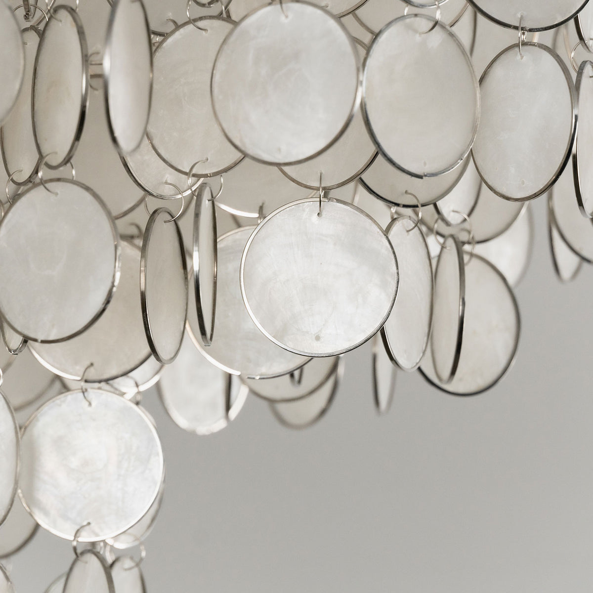 Close-up of the natural texture and iridescent finish of individual capiz shell discs.
