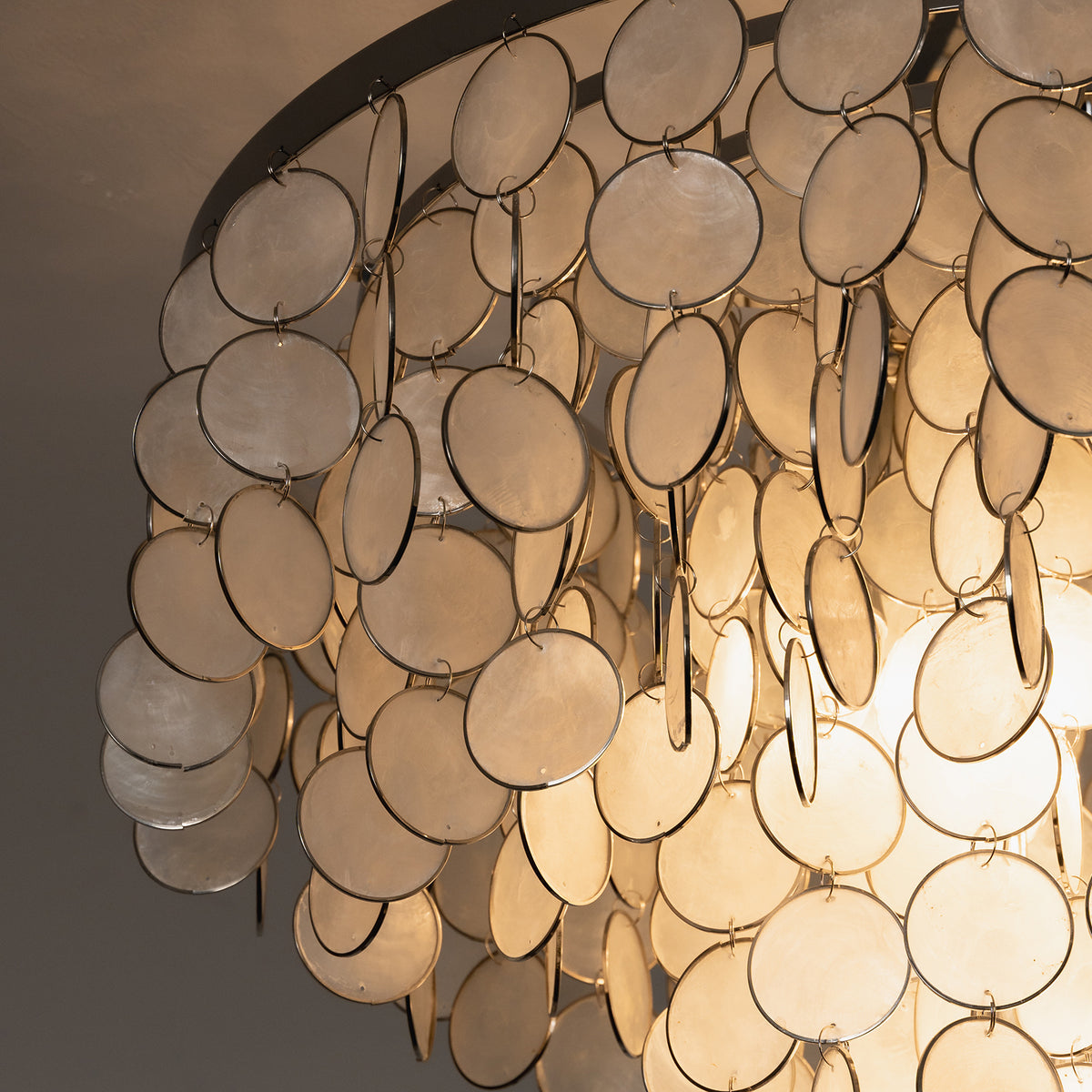 Close-up of the warm light filtering through overlapping capiz shell discs on the ceiling light.