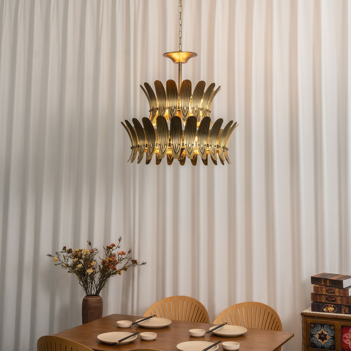 Vintage brass leaf chandelier hanging in a dining area with sheer white curtains.