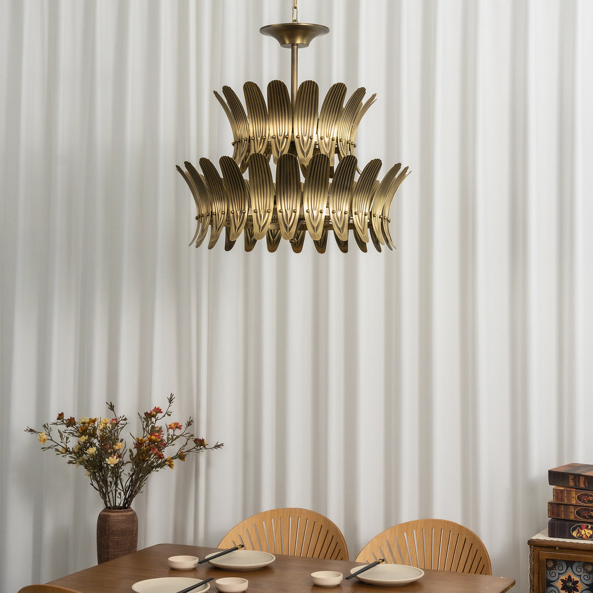 Vintage brass leaf chandelier casting warm light over a wooden dining table with floral decor.