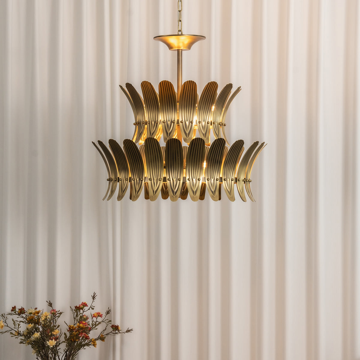 Vintage brass leaf chandelier with a warm golden glow in a curtained dining room.
