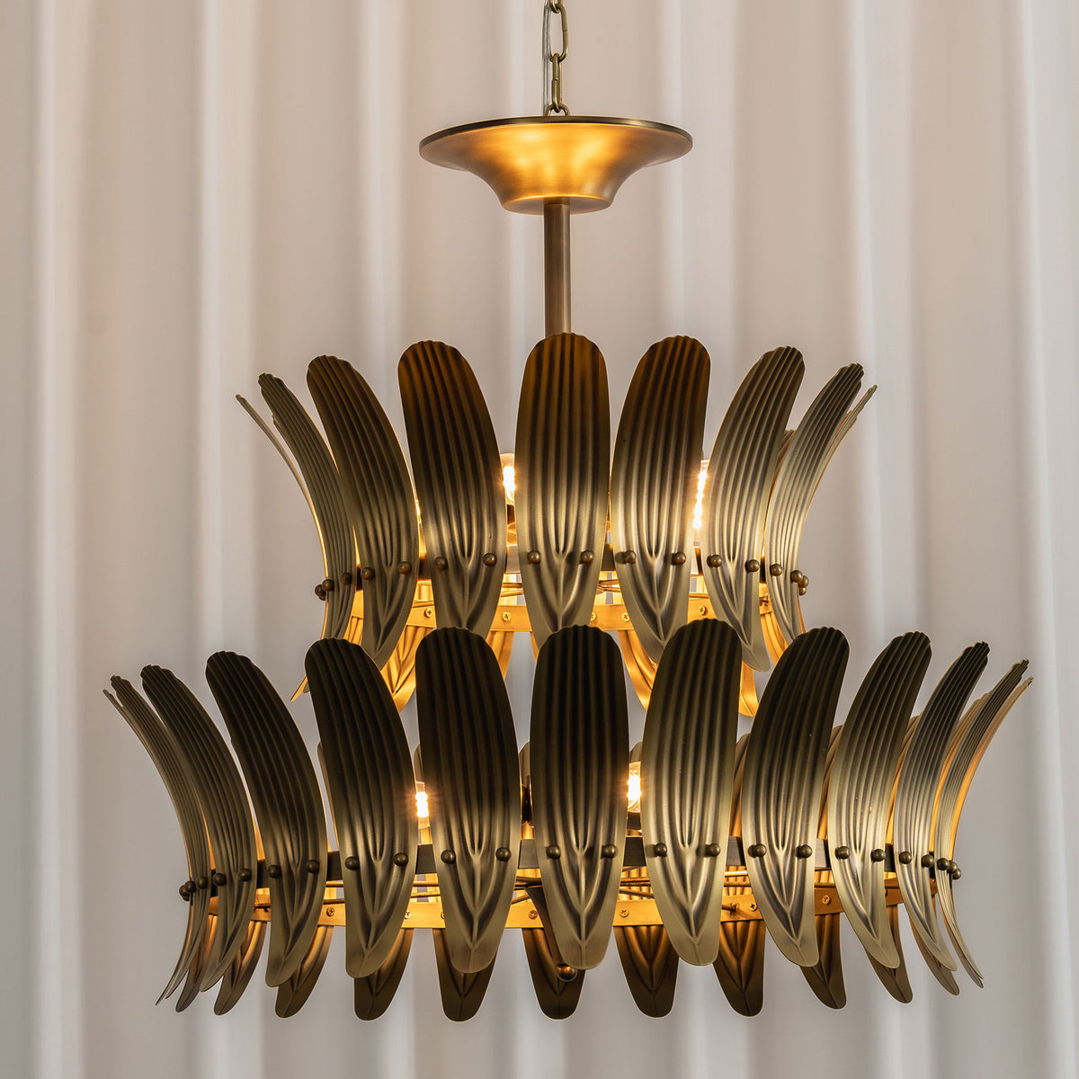 Front view of the lit vintage brass leaf chandelier, highlighting its symmetrical leaf pattern.
