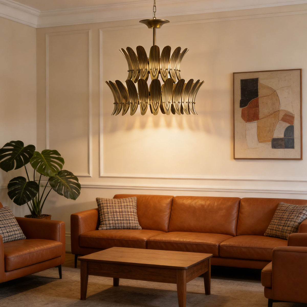 Vintage brass leaf chandelier hanging above a brown leather sofa in a modern living room.