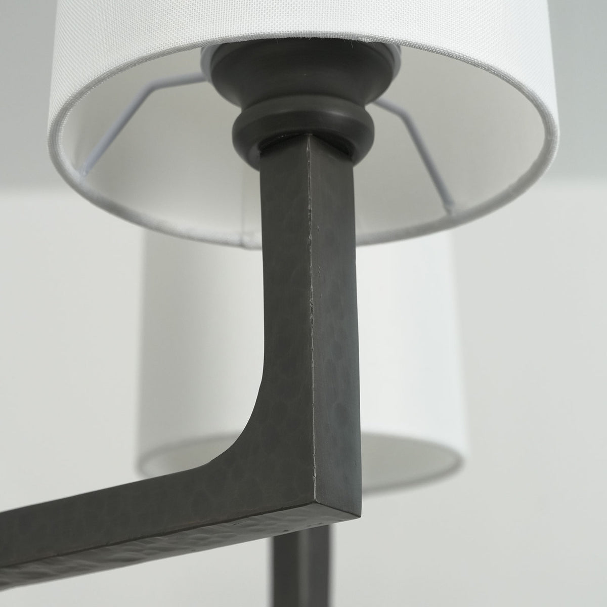 Close-up of the textured black metal arms and bracket on the Wright-inspired round chandelier.