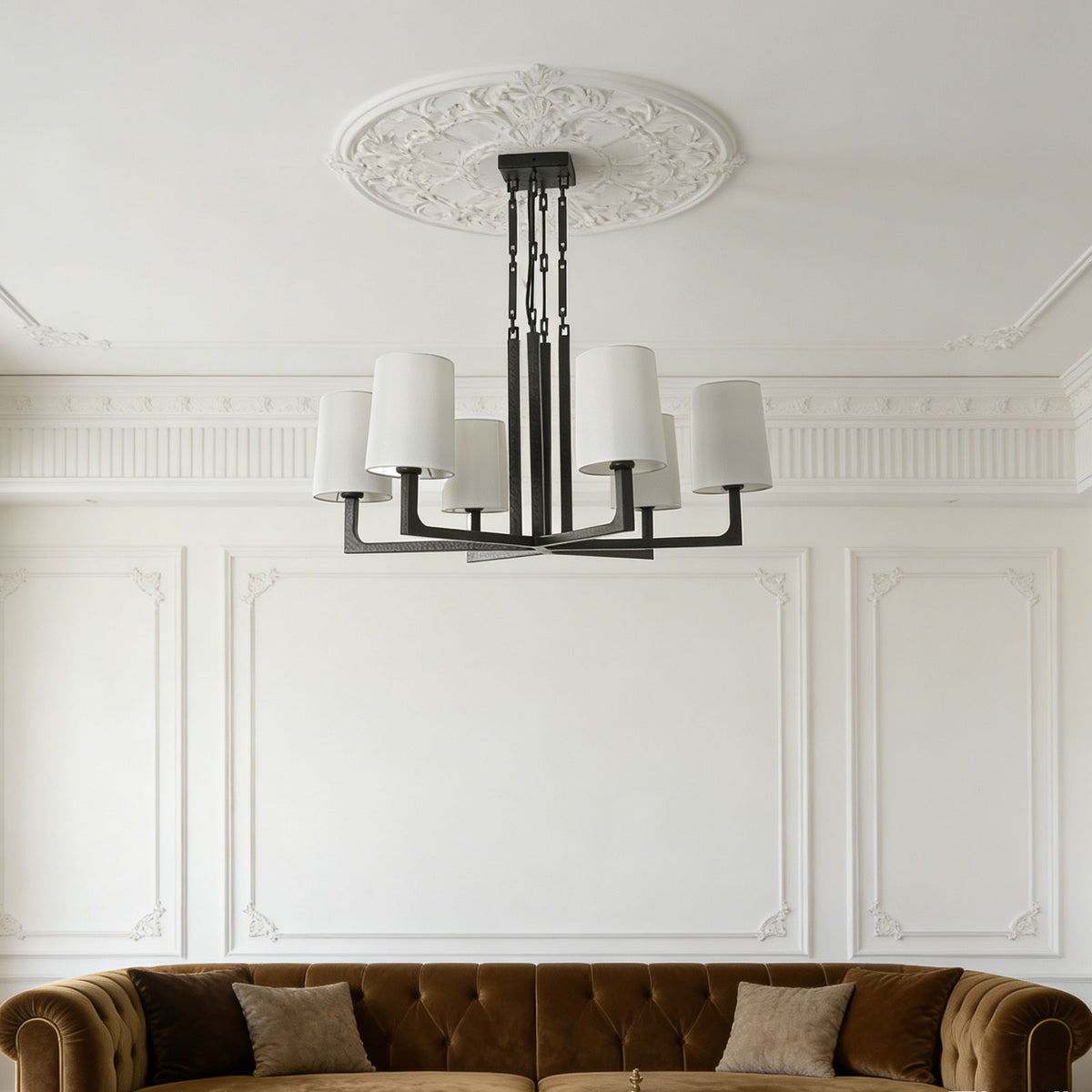 Wright-inspired round chandelier hanging above a low-profile bed in a minimalist cream-toned bedroom.