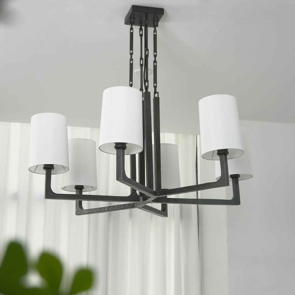 Lit Wright-inspired round chandelier, showing warm light glowing through the white fabric lampshades.