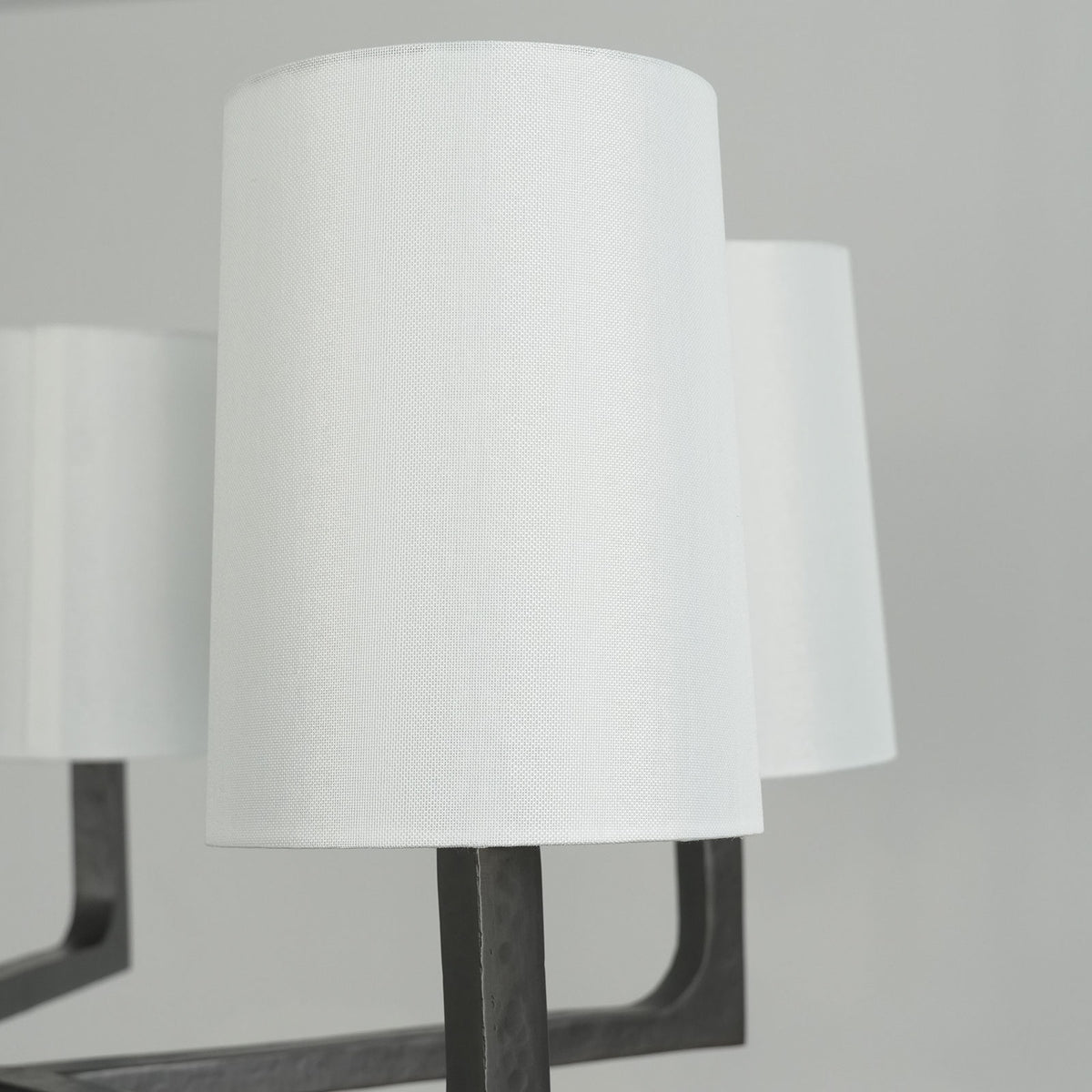 Low-angle view of a lit Wright-inspired round chandelier, highlighting the black metal arms and glowing shades.