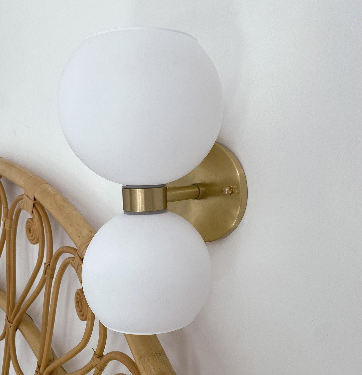 Modern wall sconce with frosted glass globes and brass finish, ideal for stylish home lighting.
