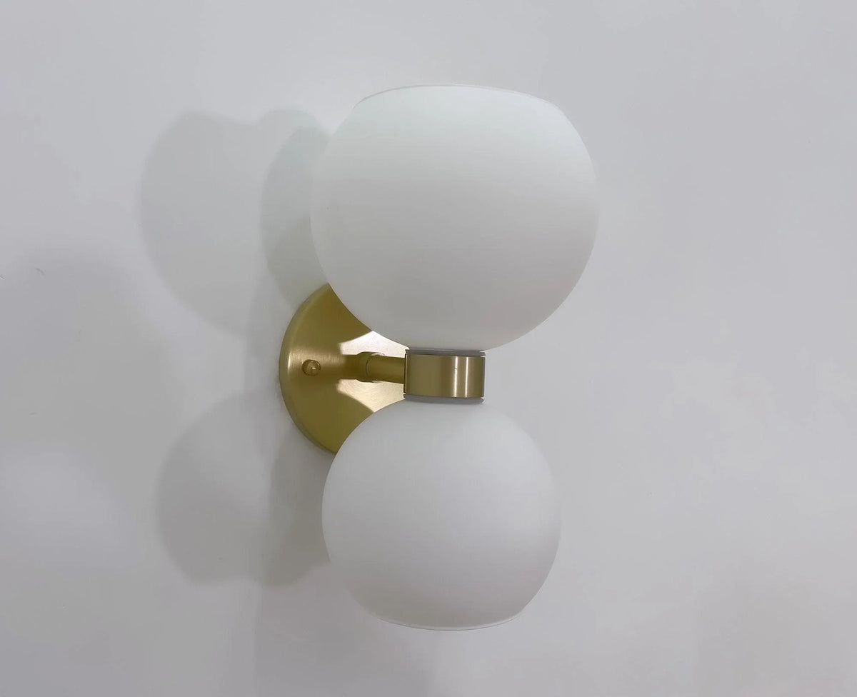 Modern brass wall sconce with frosted glass globes for stylish interior lighting