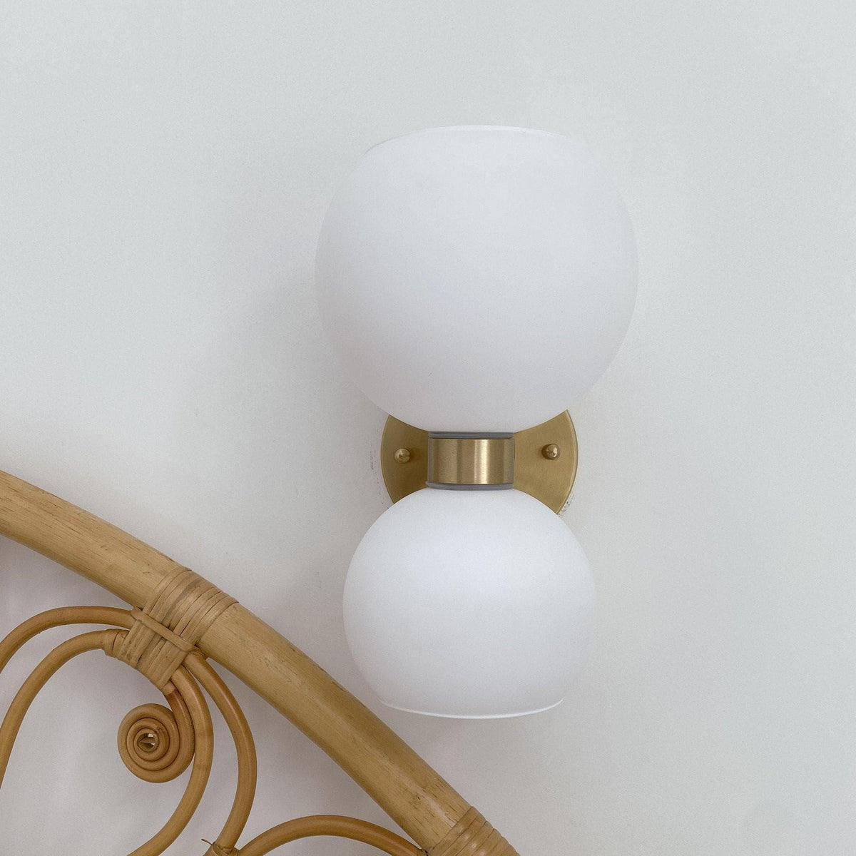 Modern wall sconce with frosted glass globes and brass finish, stylish lighting for contemporary interiors.