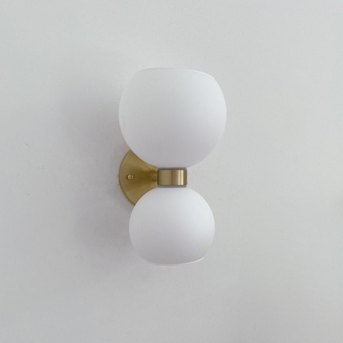 Modern wall sconce with frosted glass globes and brass finish, minimalist lighting for contemporary interiors