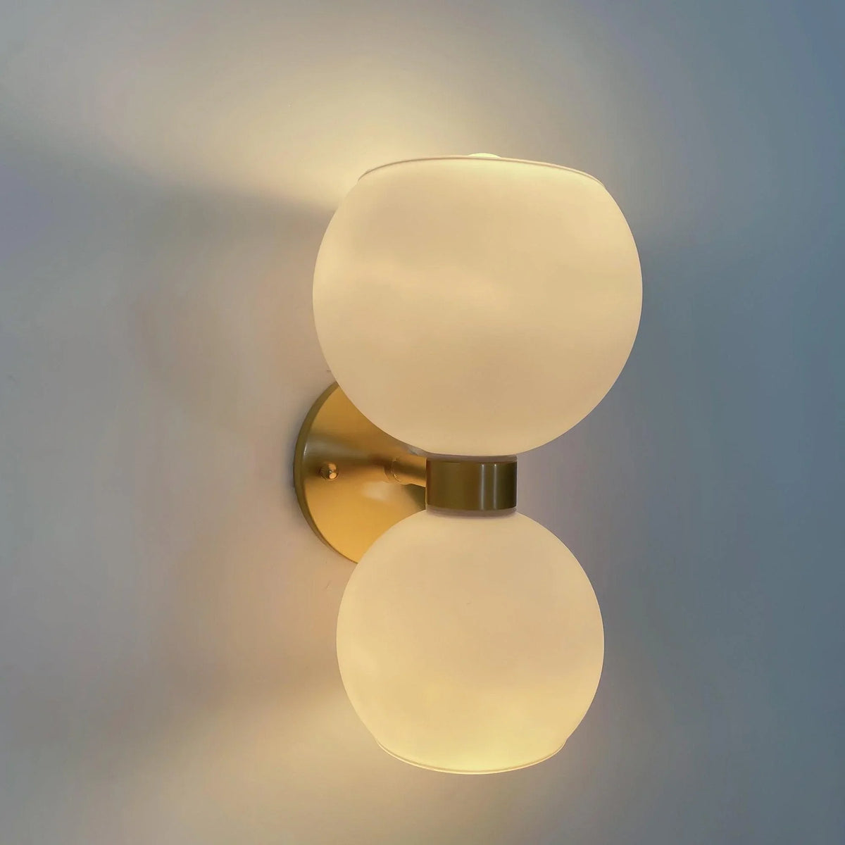 Modern wall sconce with dual frosted glass globes and brass finish, ideal for contemporary home lighting.