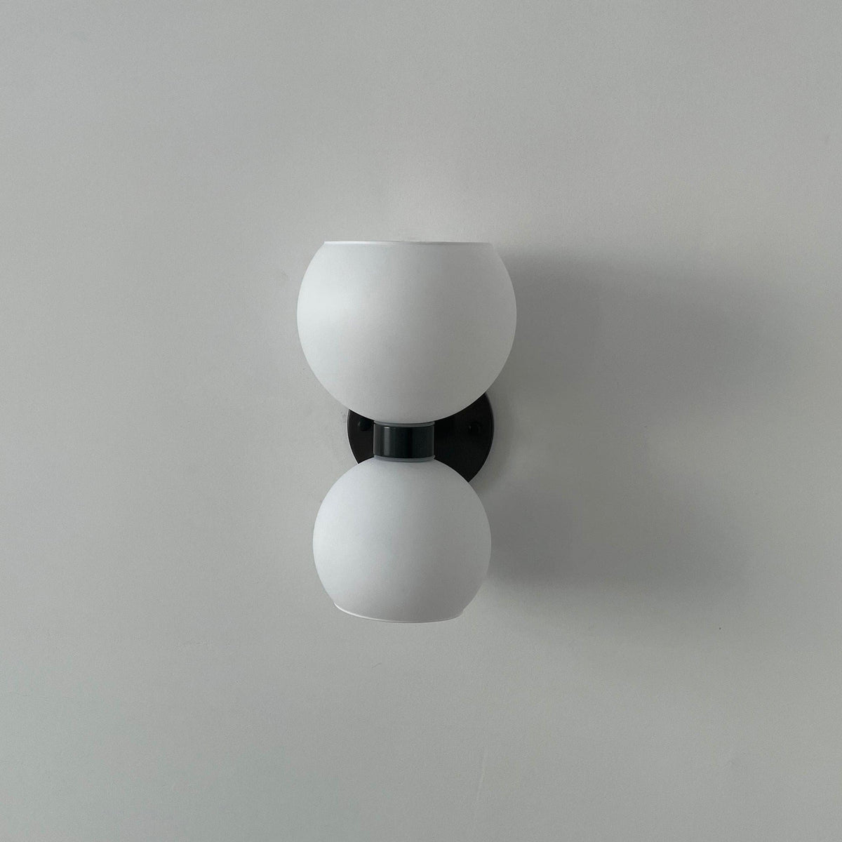 Modern wall sconce with dual frosted glass globes and black mounting bracket