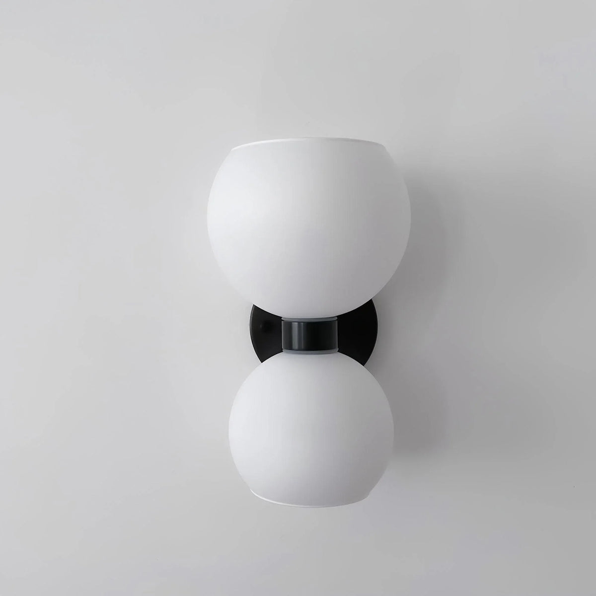 Modern wall sconce with dual frosted glass globes and black metal accents for stylish home lighting