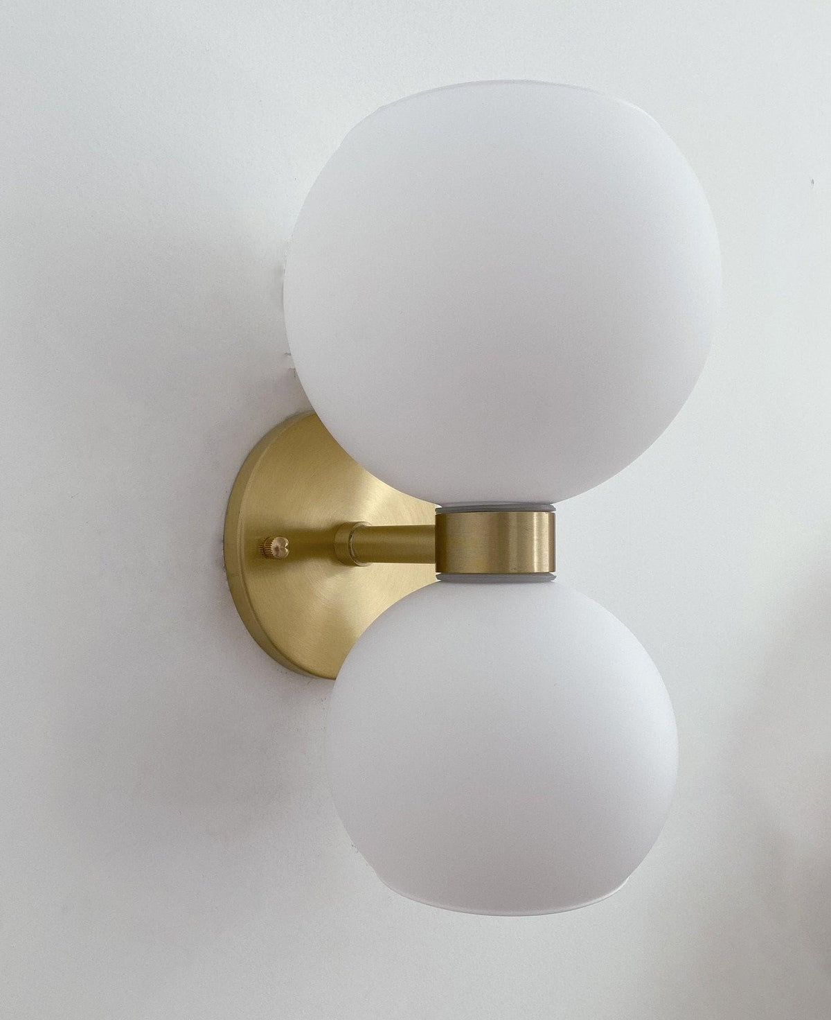 Modern brass wall sconce with frosted glass globes for stylish home lighting