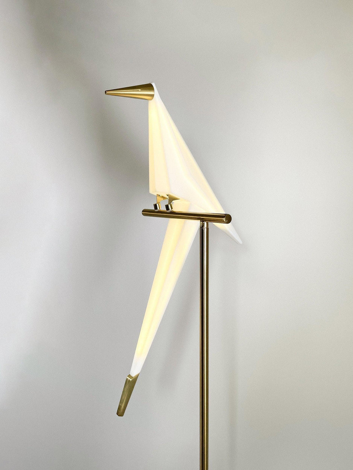 Modern bird-shaped floor lamp with brass accents and white acrylic wings, stylish home lighting