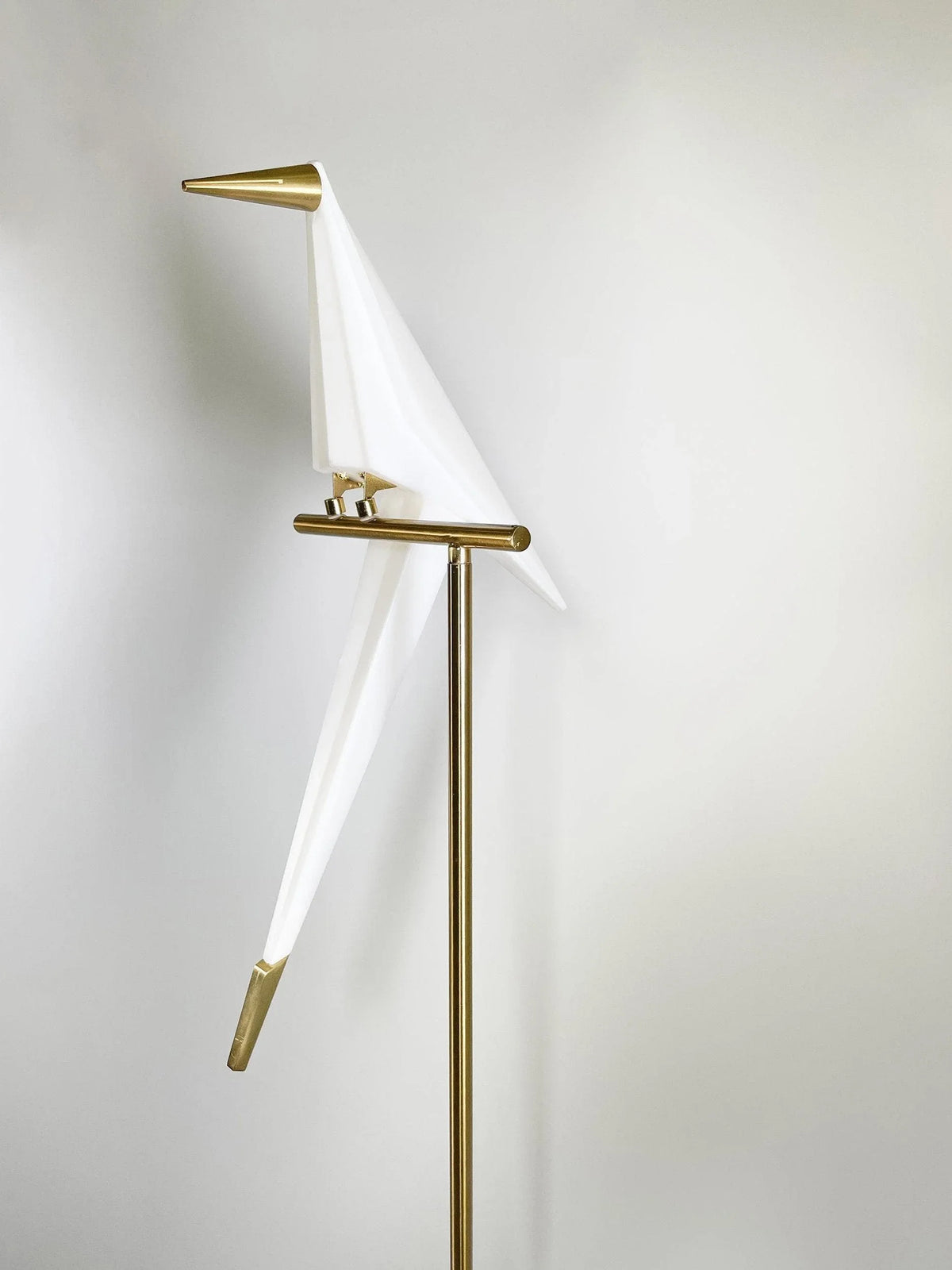 Modern bird-shaped floor lamp with white acrylic and gold metal accents, stylish home lighting