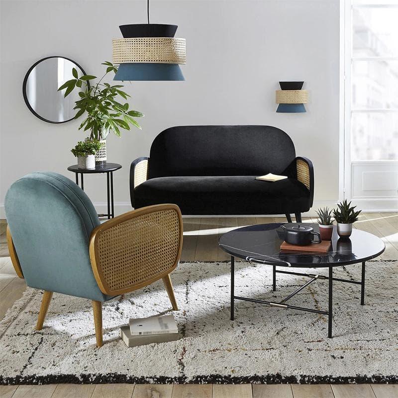 Modern living room with black velvet sofa, rattan chair, and stylish pendant lighting
