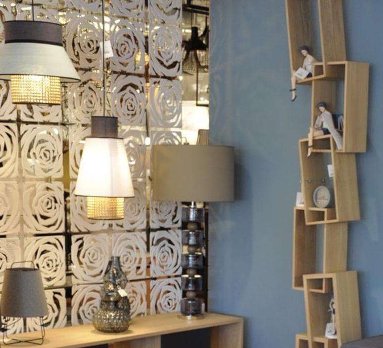 Modern crystal pendant lights with rose-patterned backdrop, stylish table lamps, and wooden shelves in a chic interior.