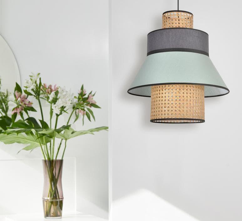 Modern layered pendant light with woven rattan and mint fabric shade, styled with fresh flowers in vase