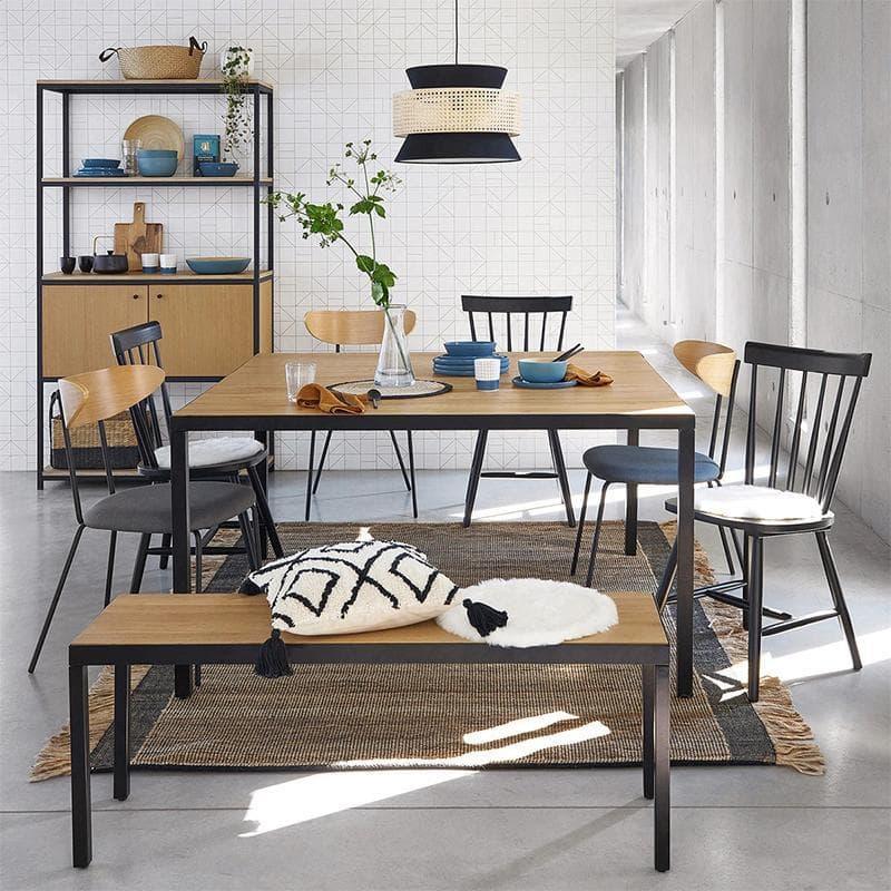 Modern dining table with black metal legs, wooden top, matching chairs, and pendant light in minimalist room